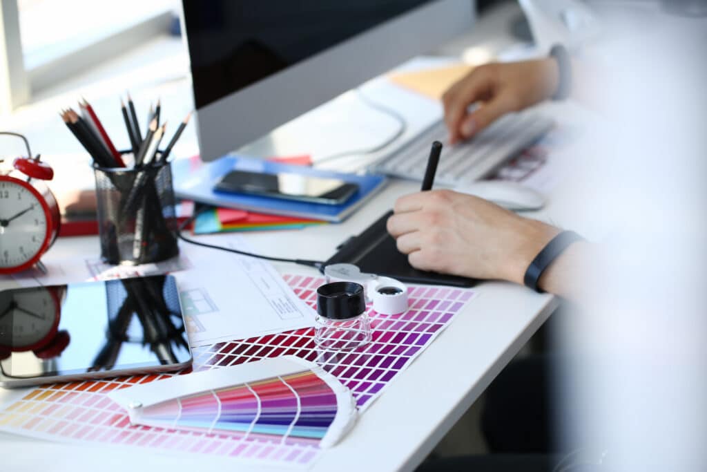 person designing on computer with color swatches on desk