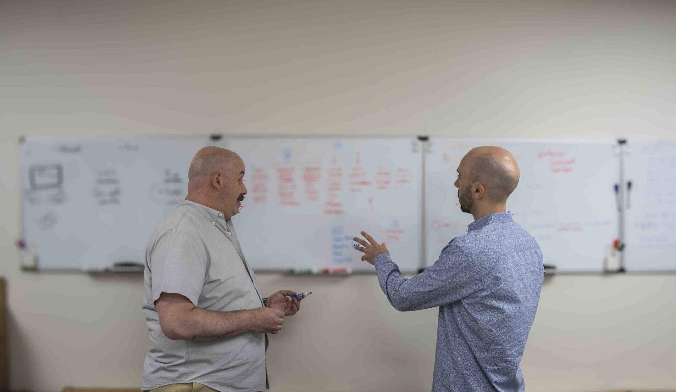 Tetrafab-Design-Ideation two men discussing in front of a white board while gesturing at it
